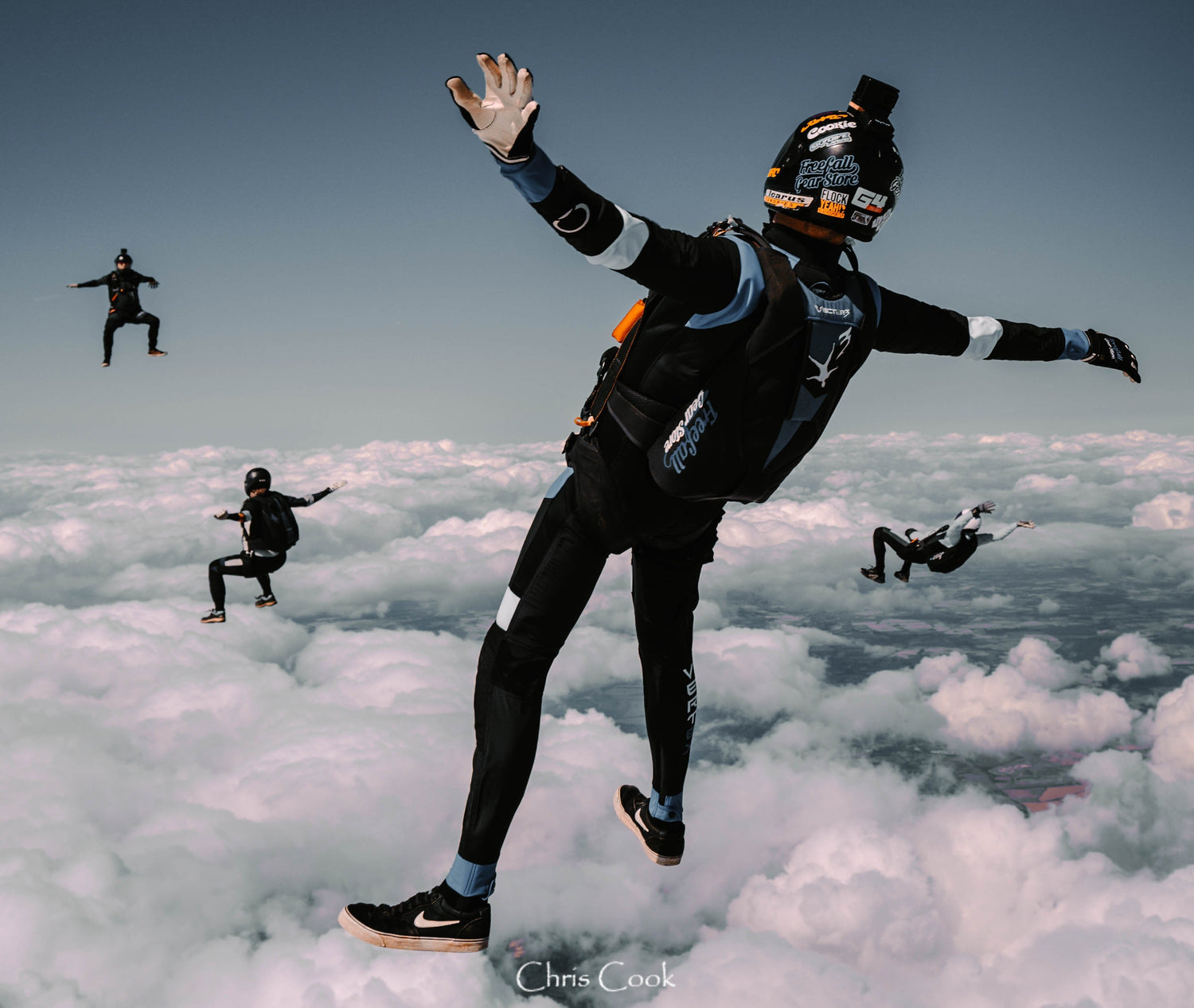 Person skydiving over a cloud cover with other skydivers in the background.